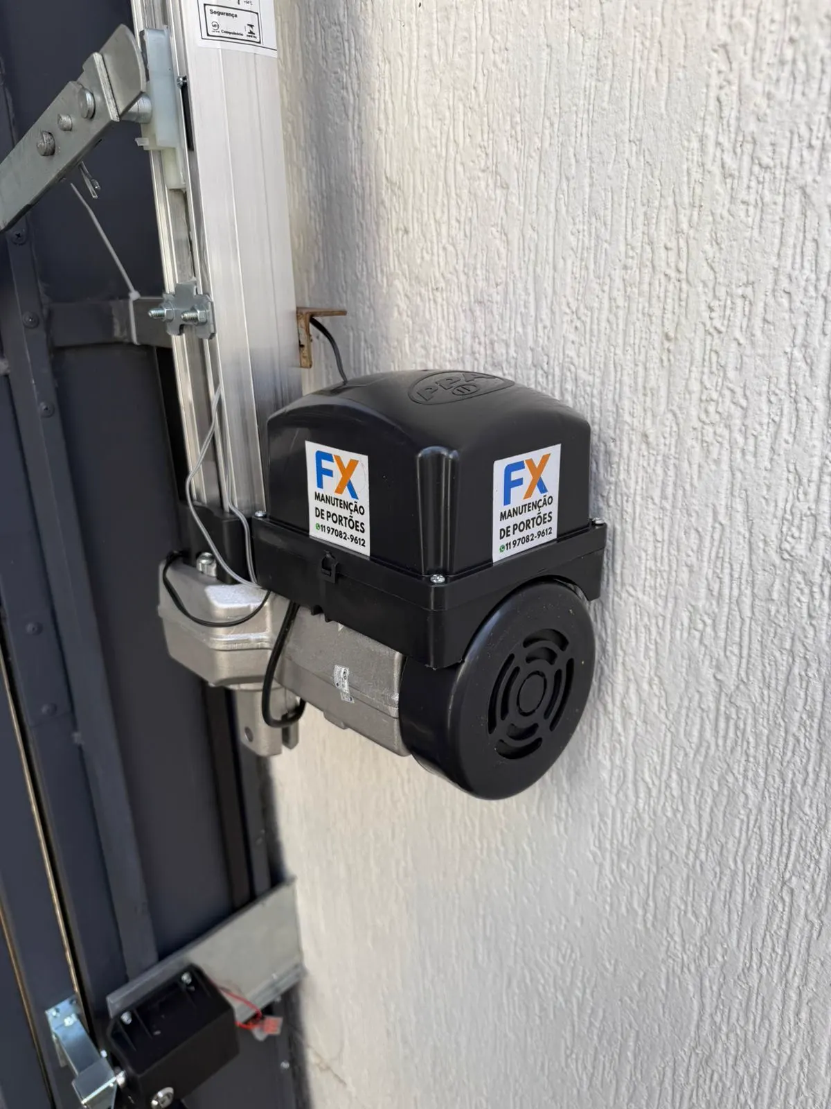 Motor de portão automático com central e cremalheira instalados em muro branco